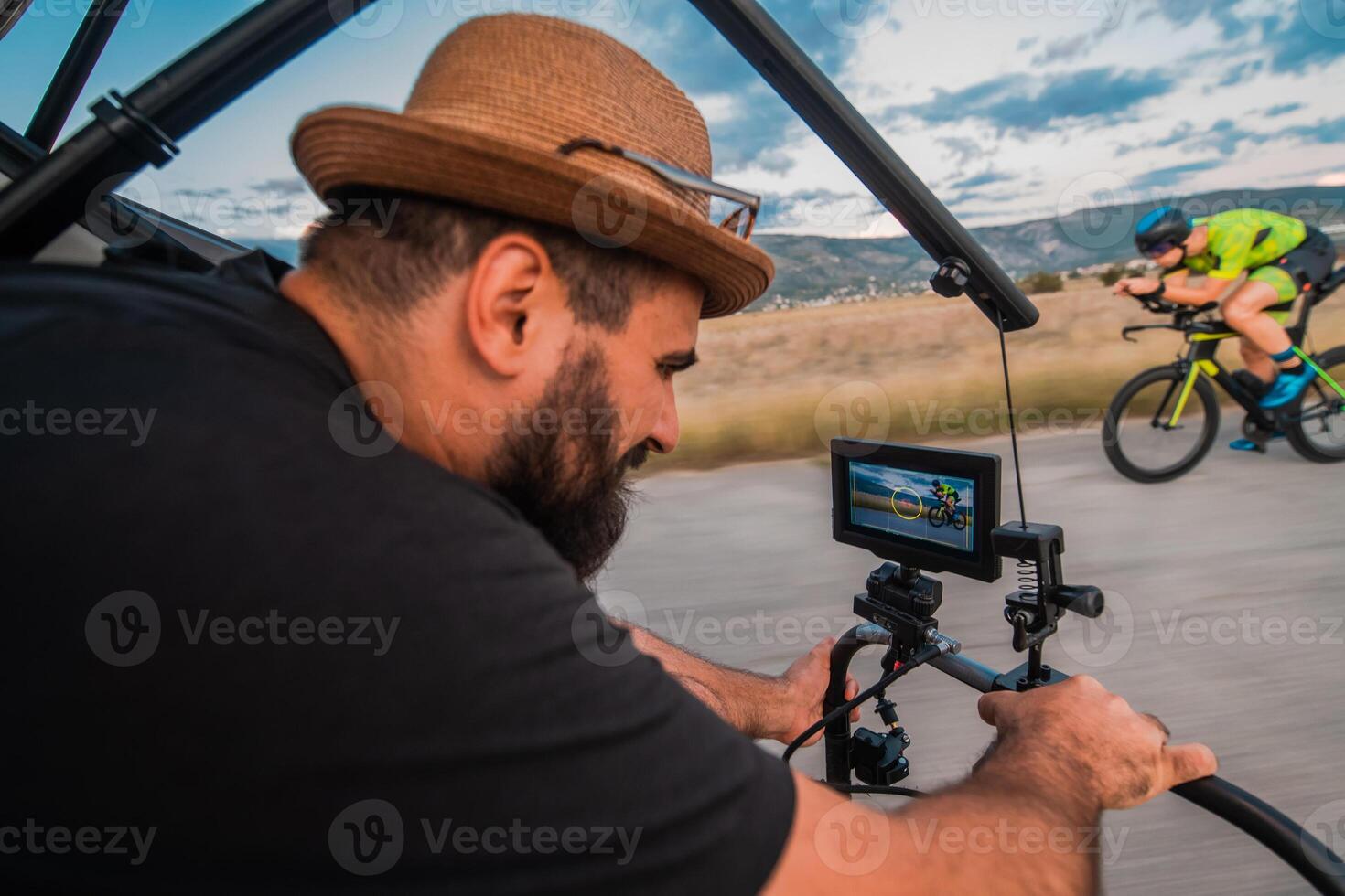 A videographer recording a triathlete riding his bike preparing for an upcoming marathon.Athlete's physical endurance and the dedication required to succeed in the sport. photo