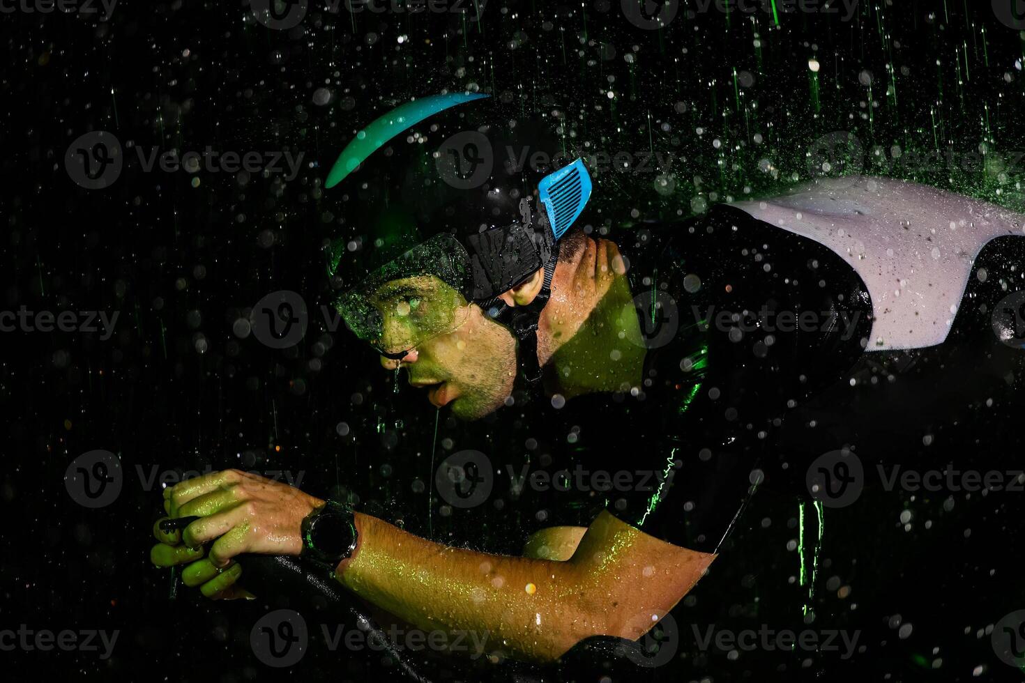 A triathlete braving the rain as he cycles through the night, preparing himself for the upcoming marathon photo