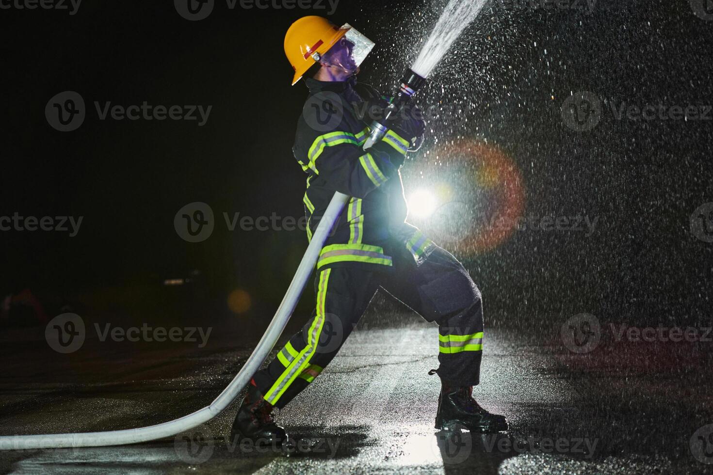 Firefighter using a water hose to eliminate a fire hazard. Team of firemen in the dangerous rescue mission. photo
