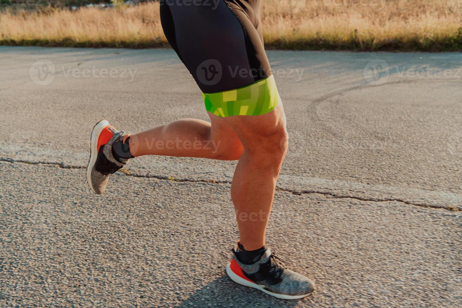 Closeup of muscular legs of a triathlete in professional equipment running early in the morning, preparing for a marathon, dedication to sports and readiness for marathon challenges photo
