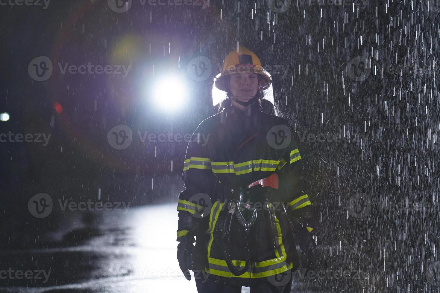 A determined female firefighter in a professional uniform striding through the dangerous, rainy night on a daring rescue mission, showcasing her unwavering bravery and commitment to saving lives. photo
