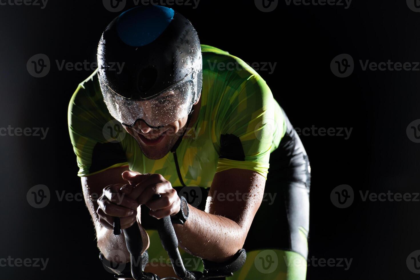 A triathlete rides his bike in the darkness of night, pushing himself to prepare for a marathon. The contrast between the darkness and the light of his bike creates a sense of drama and highlights the photo