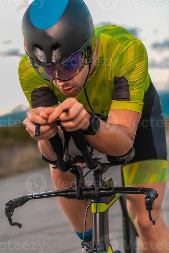 Triathlete riding his bicycle during sunset, preparing for a marathon. The warm colors of the sky provide a beautiful backdrop for his determined and focused effort. photo