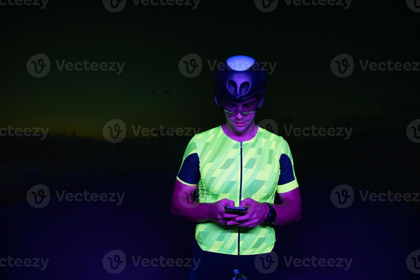A triathlete using a smartphone while taking a break from a hard night's cycling training photo