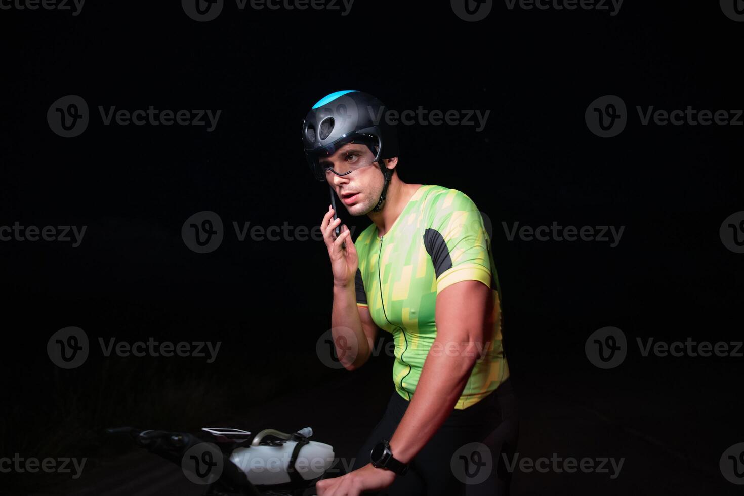 A triathlete using a smartphone while taking a break from a hard night's cycling training photo