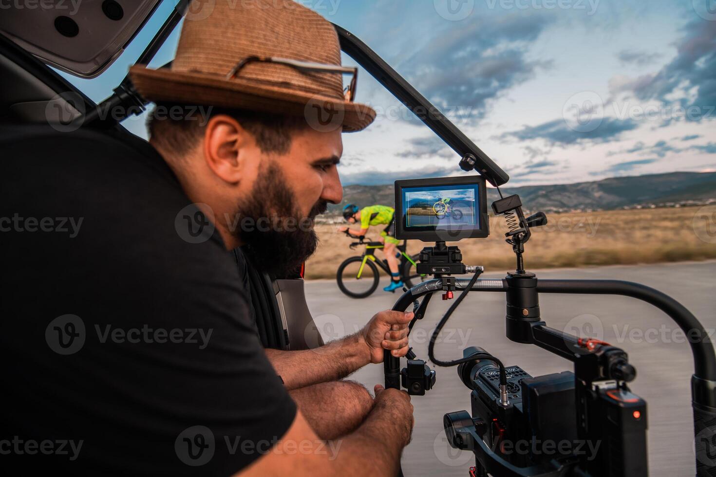 A videographer recording a triathlete riding his bike preparing for an upcoming marathon.Athlete's physical endurance and the dedication required to succeed in the sport. photo