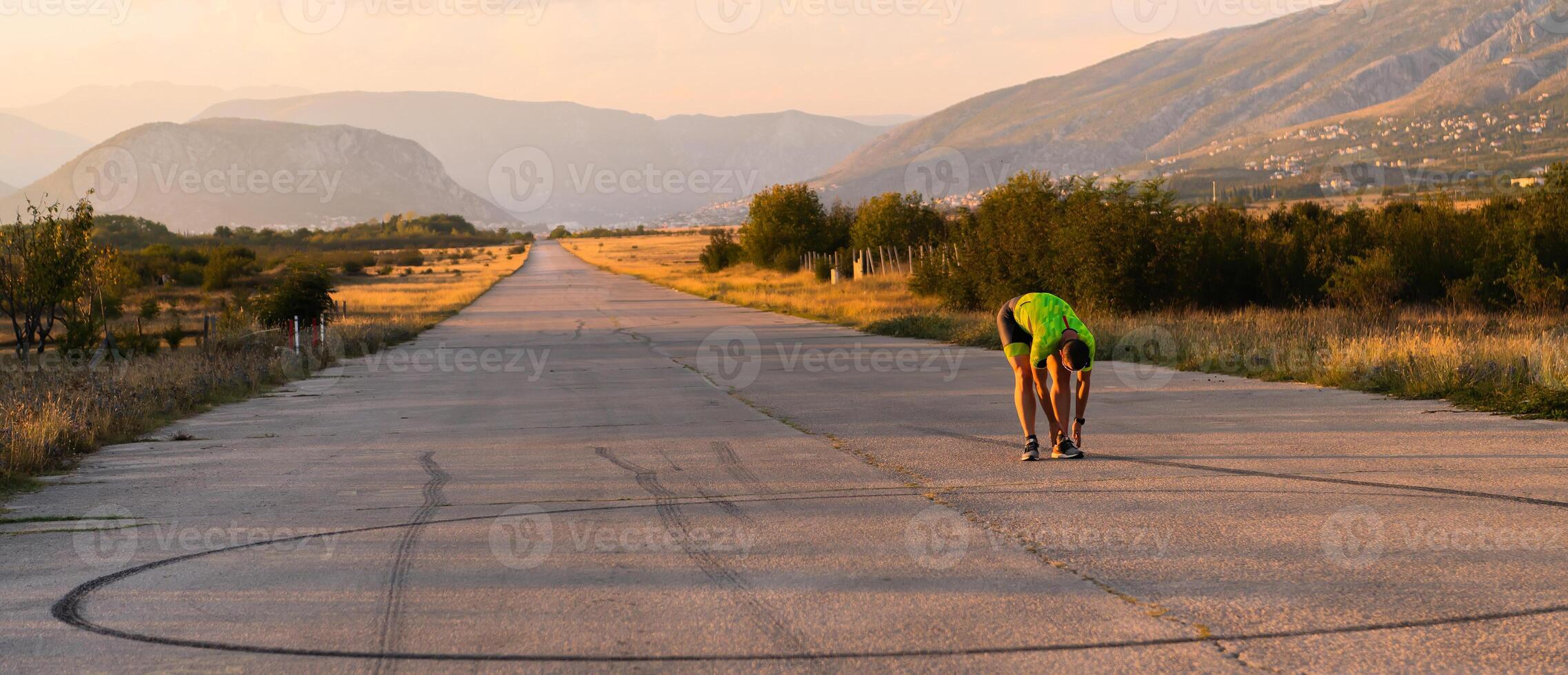 In the early morning light, the triathlete preparing for run by tying his shoes. With focused determination and unwavering dedication, he readies himself for the physical and mental challenge ahead photo
