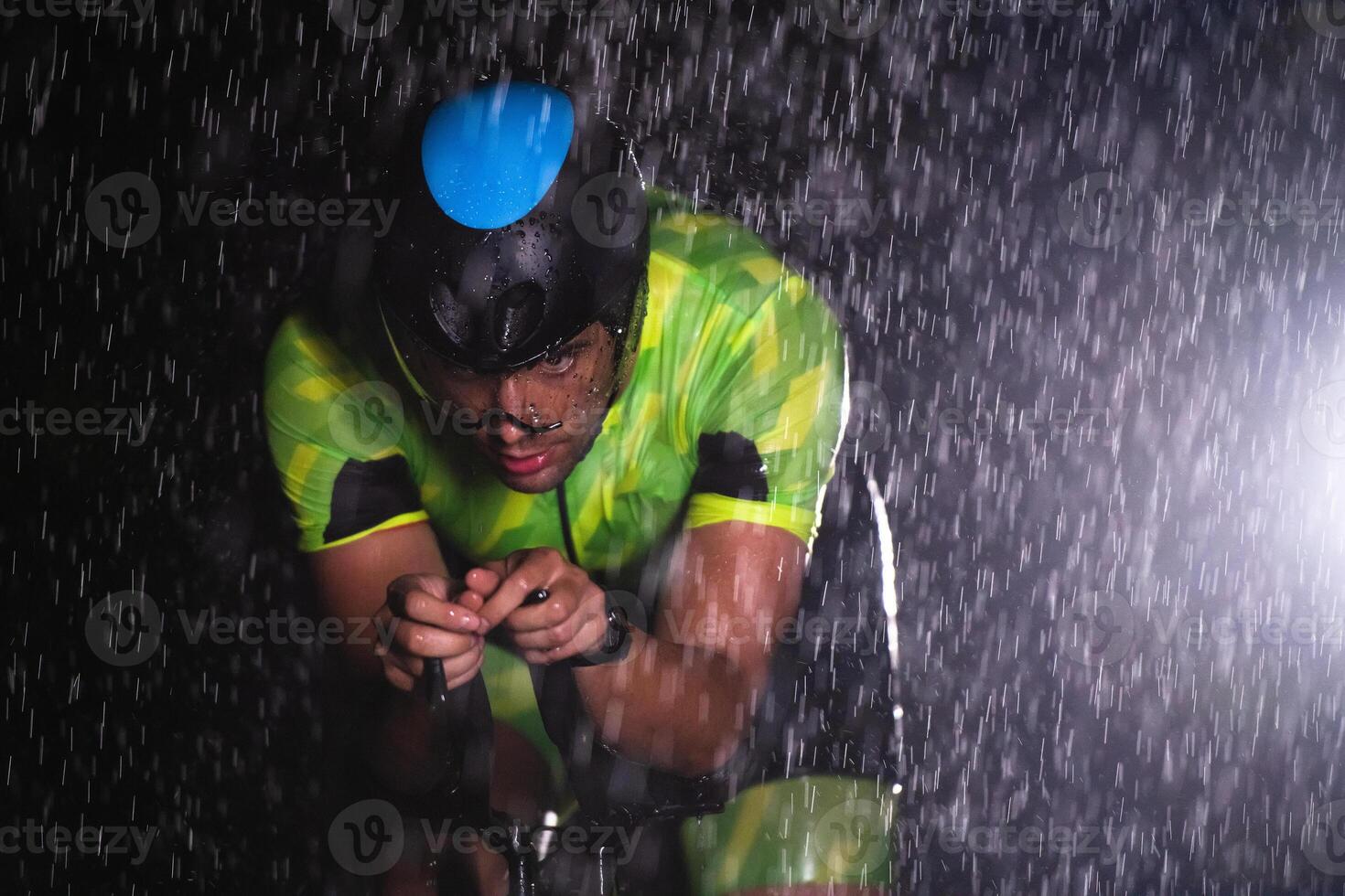 A triathlete braving the rain as he cycles through the night, preparing himself for the upcoming marathon photo