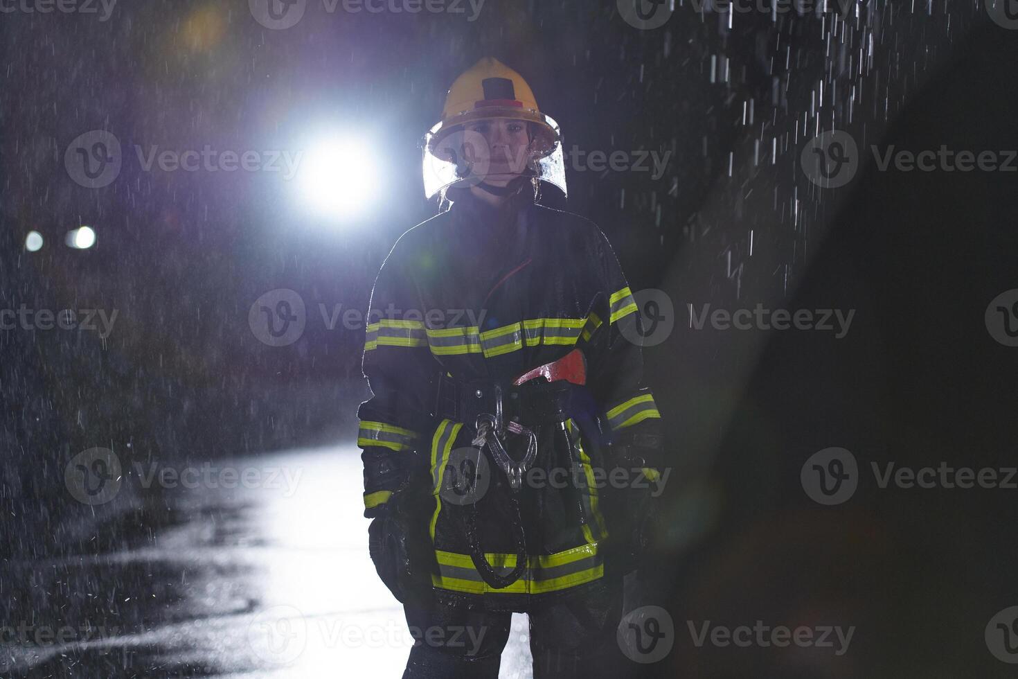 A determined female firefighter in a professional uniform striding through the dangerous, rainy night on a daring rescue mission, showcasing her unwavering bravery and commitment to saving lives. photo