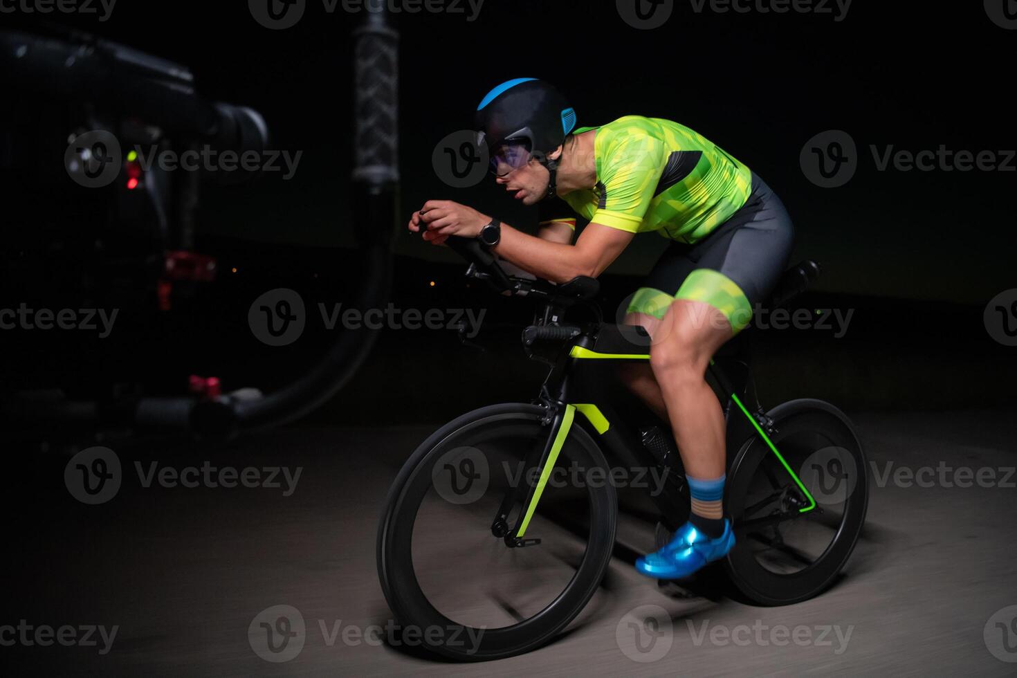 A videographer recording a triathlete riding his bike preparing for an upcoming marathon.Athlete's physical endurance and the dedication required to succeed in the sport. photo