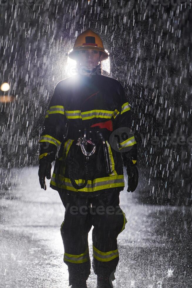 A determined female firefighter in a professional uniform striding through the dangerous, rainy night on a daring rescue mission, showcasing her unwavering bravery and commitment to saving lives. photo