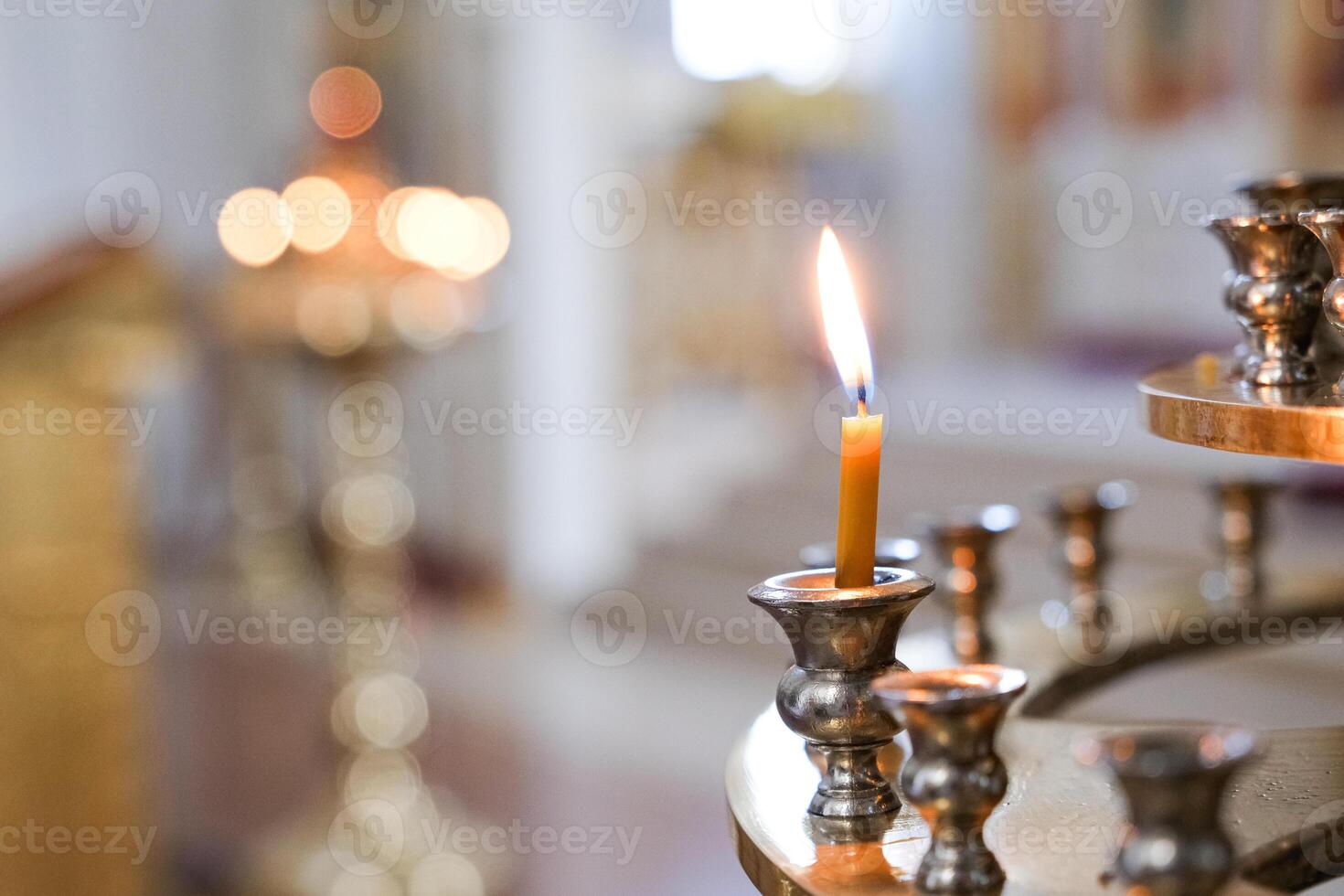 A candle lights in the temple opposite the icons photo