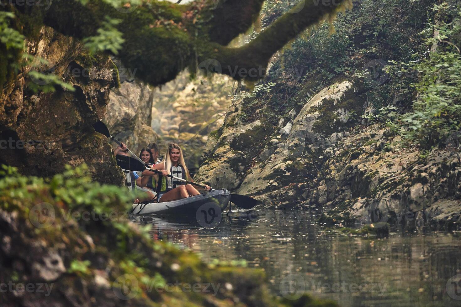 A group of friends enjoying having fun and kayaking while exploring the calm river, surrounding forest and large natural river canyons photo