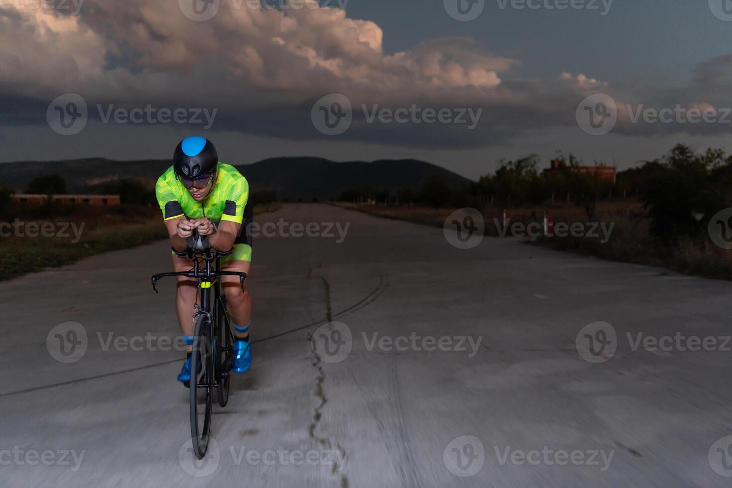 A triathlete rides his bike in the darkness of night, pushing himself to prepare for a marathon. The contrast between the darkness and the light of his bike creates a sense of drama and highlights the photo