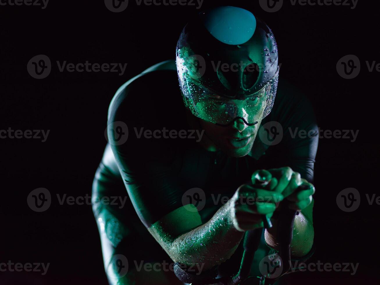 A triathlete rides his bike in the darkness of night, pushing himself to prepare for a marathon. The contrast between the darkness and the light of his bike creates a sense of drama and highlights the photo