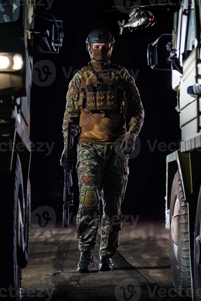 A soldier marching through the dark of night, accompanied by two military trucks, as he embarks on a perilous military mission, embodying the unwavering determination, teamwork, and preparedness photo