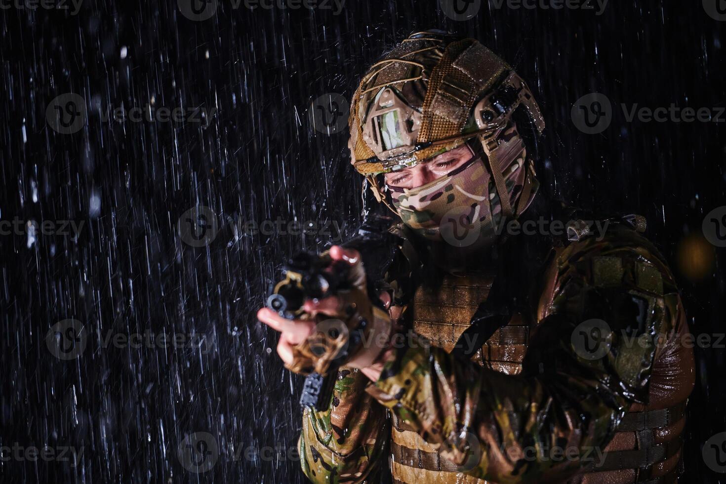 Army soldier in Combat Uniforms with an assault rifle, plate carrier and combat helmet going on a dangerous mission on a rainy night. photo