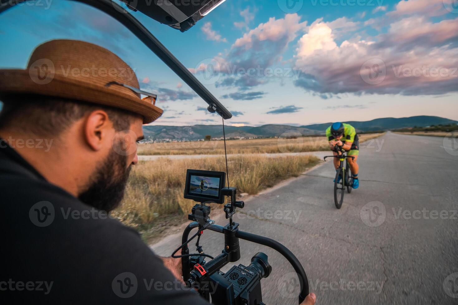 A videographer recording a triathlete riding his bike preparing for an upcoming marathon.Athlete's physical endurance and the dedication required to succeed in the sport. photo