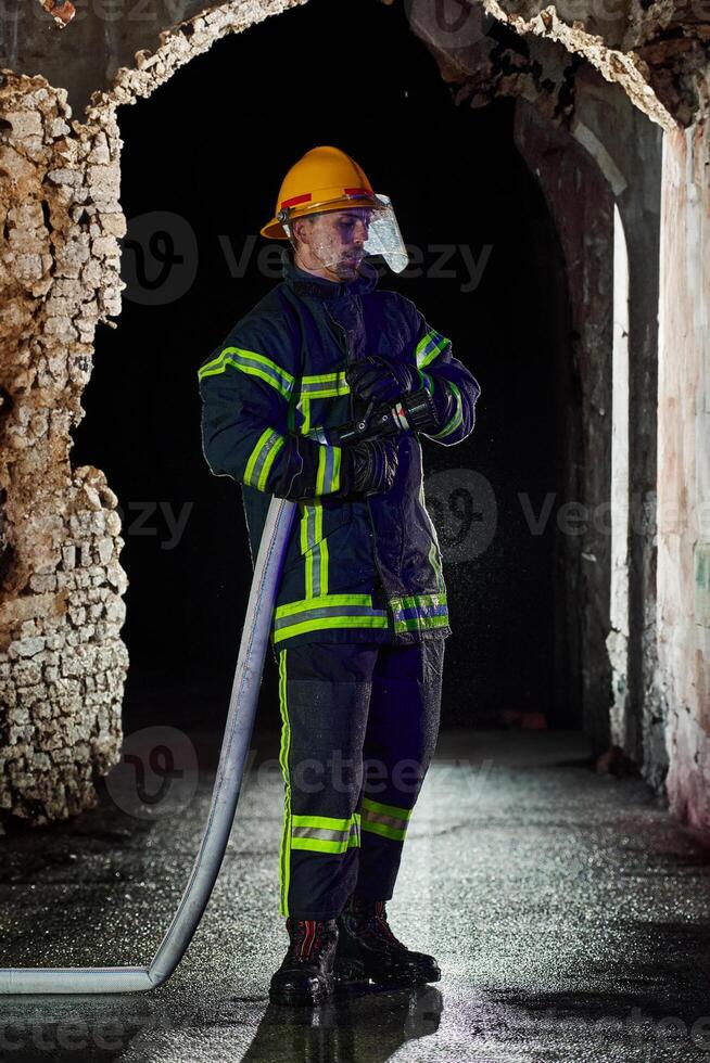 Firefighter using a water hose to eliminate a fire hazard. Team of female and male firemen in dangerous rescue mission. photo