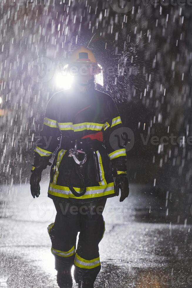 A determined female firefighter in a professional uniform striding through the dangerous, rainy night on a daring rescue mission, showcasing her unwavering bravery and commitment to saving lives. photo