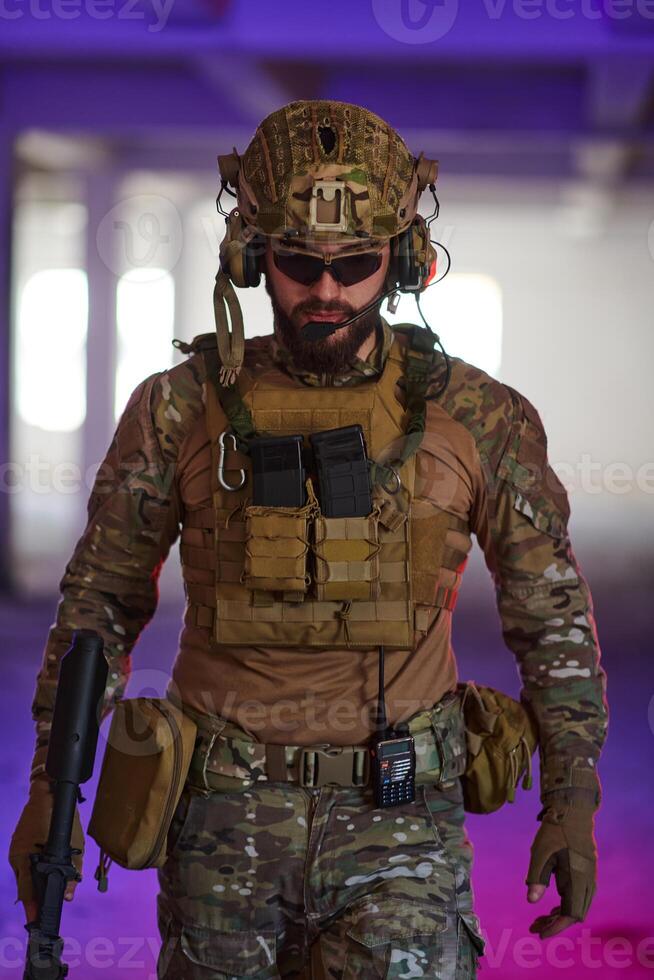 A professional soldier undertakes a perilous mission in an abandoned building illuminated by neon blue and purple lights photo