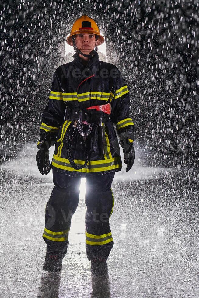 A determined female firefighter in a professional uniform striding through the dangerous, rainy night on a daring rescue mission, showcasing her unwavering bravery and commitment to saving lives. photo