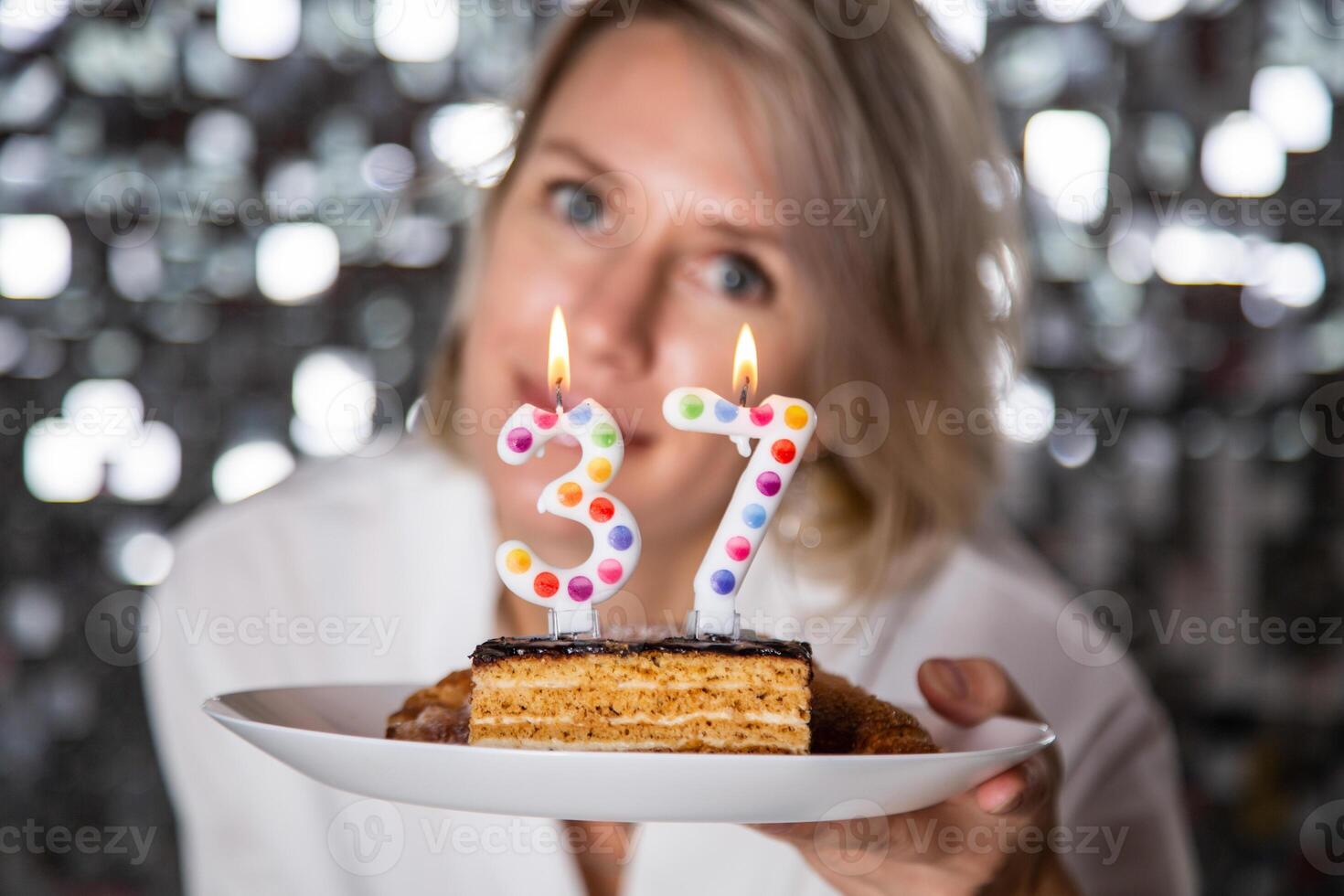 woman blowing candles on birthday cake, studio shot photo