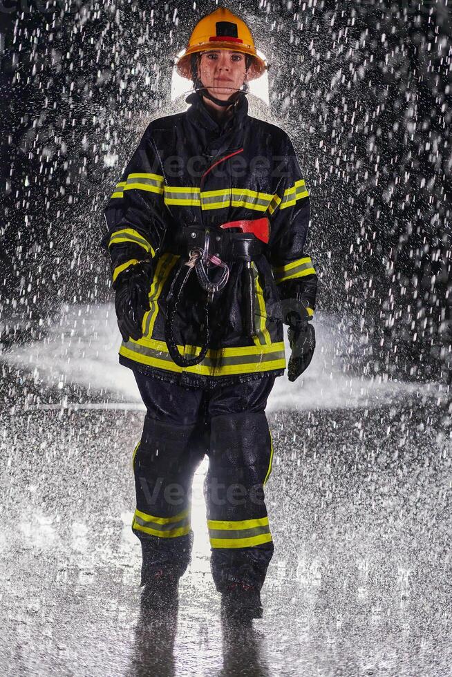 A determined female firefighter in a professional uniform striding through the dangerous, rainy night on a daring rescue mission, showcasing her unwavering bravery and commitment to saving lives. photo