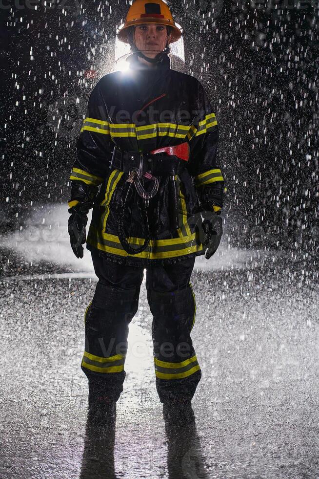 A determined female firefighter in a professional uniform striding through the dangerous, rainy night on a daring rescue mission, showcasing her unwavering bravery and commitment to saving lives. photo