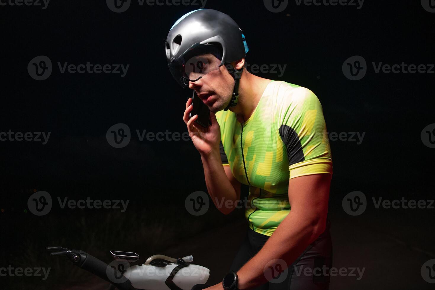 A triathlete using a smartphone while taking a break from a hard night's cycling training photo