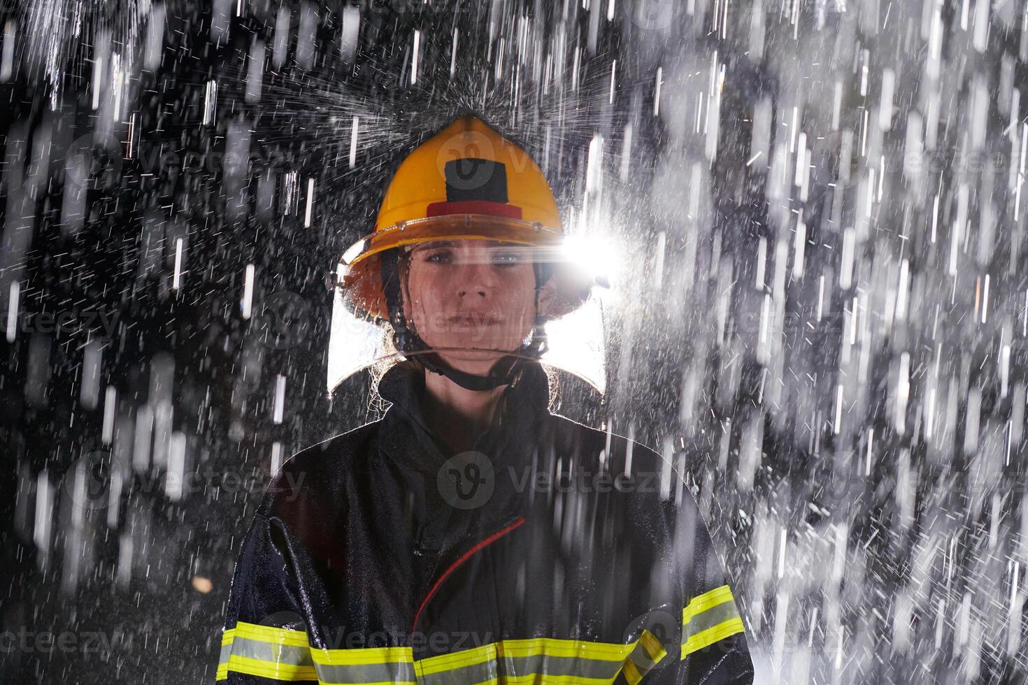 A determined female firefighter in a professional uniform striding through the dangerous, rainy night on a daring rescue mission, showcasing her unwavering bravery and commitment to saving lives. photo