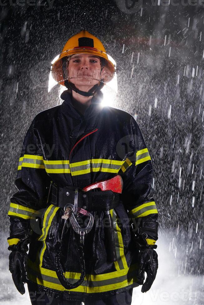 A determined female firefighter in a professional uniform striding through the dangerous, rainy night on a daring rescue mission, showcasing her unwavering bravery and commitment to saving lives. photo