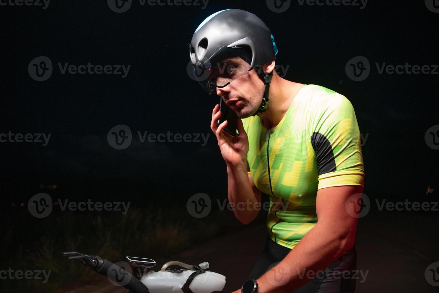 A triathlete using a smartphone while taking a break from a hard night's cycling training photo
