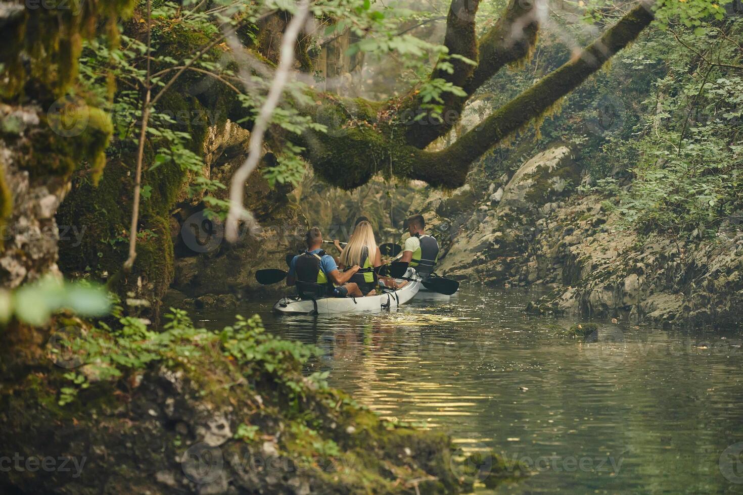 A group of friends enjoying having fun and kayaking while exploring the calm river, surrounding forest and large natural river canyons photo