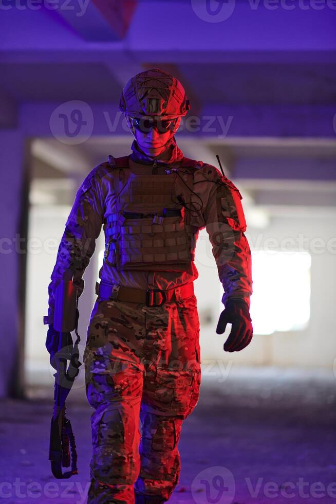 A professional soldier undertakes a perilous mission in an abandoned building illuminated by neon blue and purple lights photo