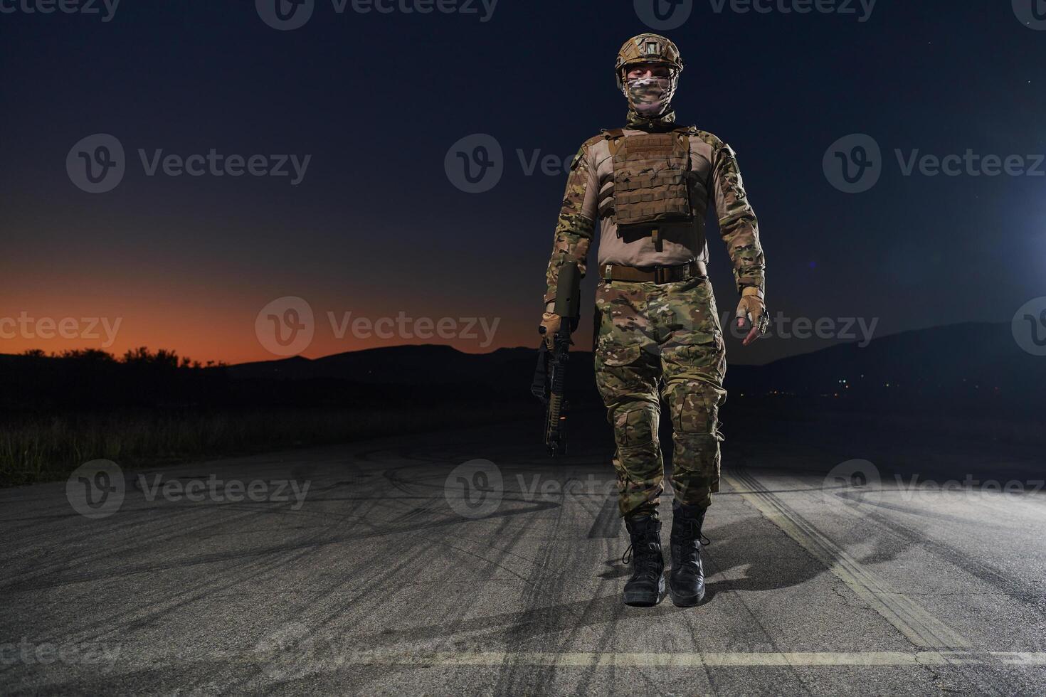 A professional soldier in full military gear striding through the dark night as he embarks on a perilous military mission photo
