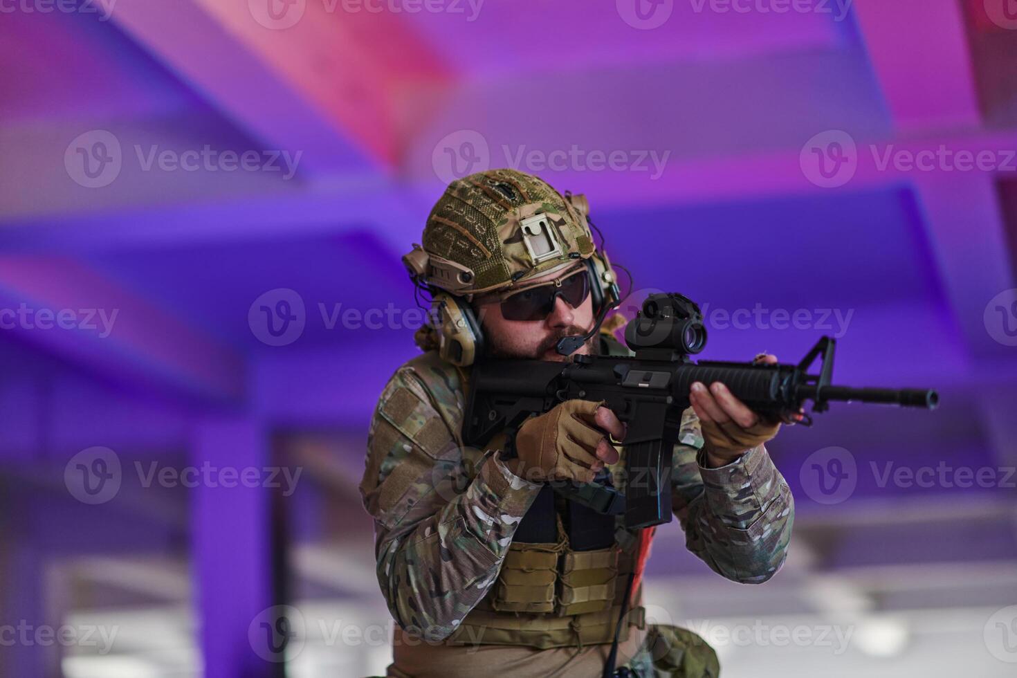 A professional soldier undertakes a perilous mission in an abandoned building illuminated by neon blue and purple lights photo