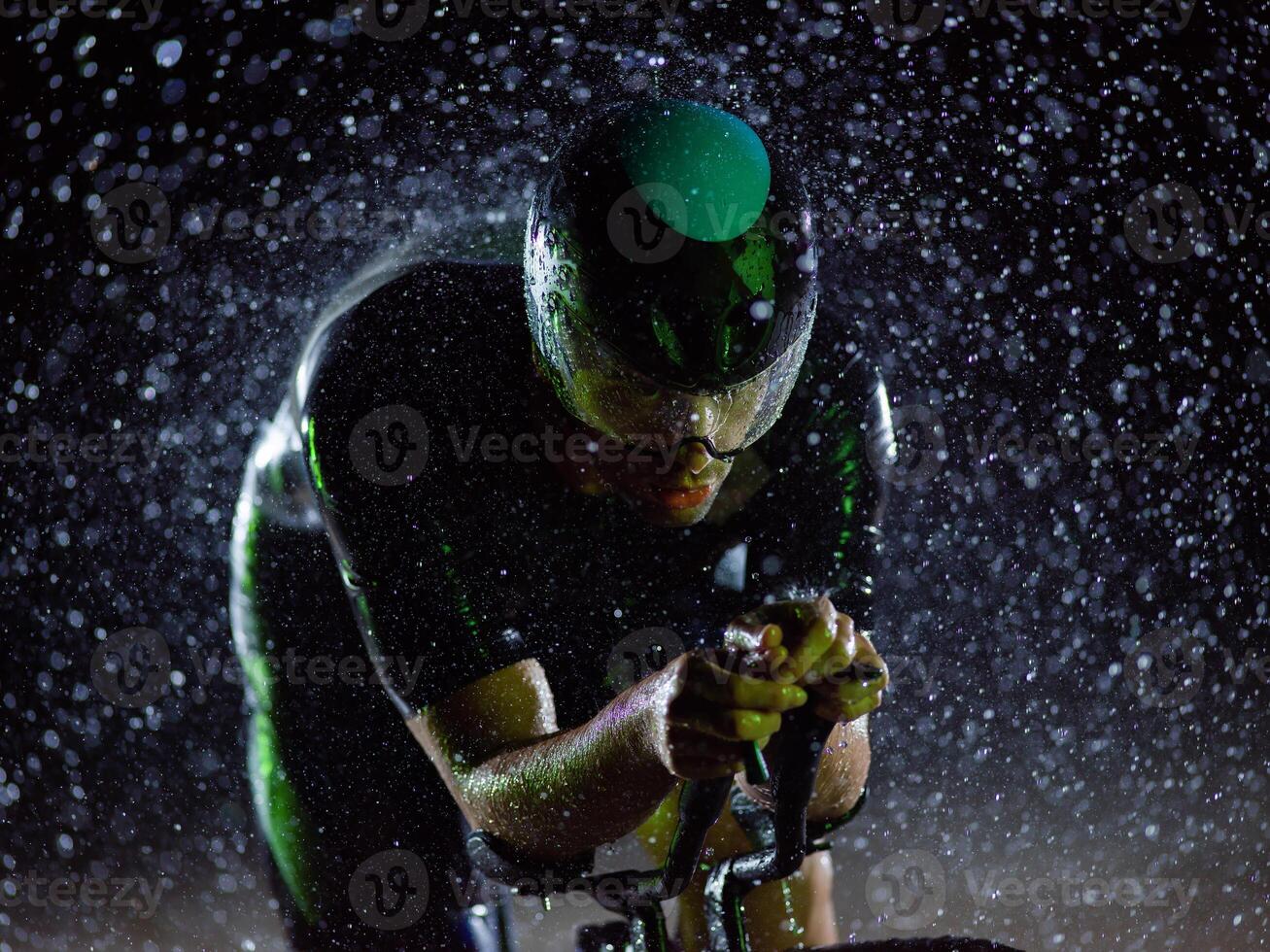 A triathlete braving the rain as he cycles through the night, preparing himself for the upcoming marathon photo
