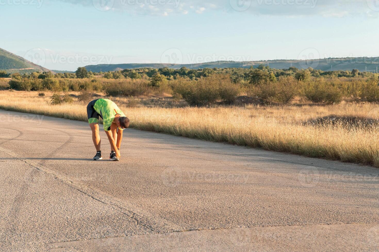 In the early morning light, the triathlete preparing for run by tying his shoes. With focused determination and unwavering dedication, he readies himself for the physical and mental challenge ahead photo