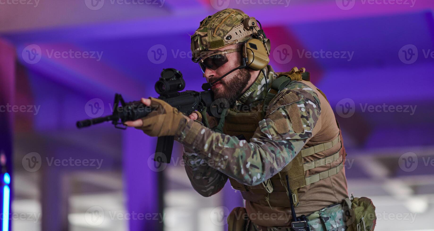 A professional soldier undertakes a perilous mission in an abandoned building illuminated by neon blue and purple lights photo