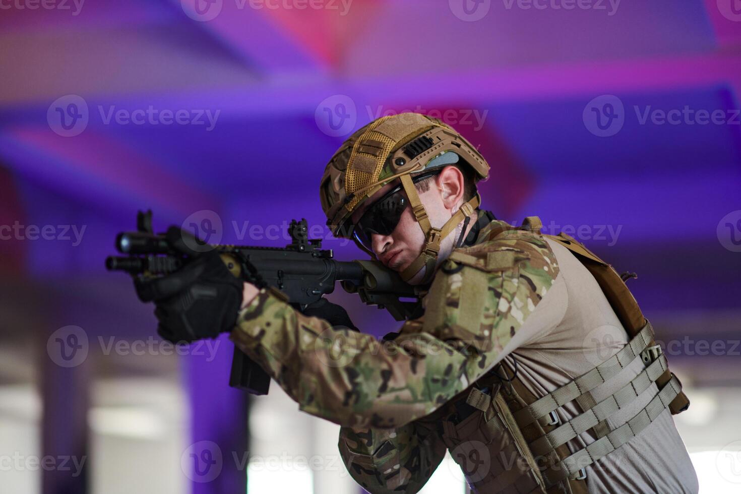 A professional soldier undertakes a perilous mission in an abandoned building illuminated by neon blue and purple lights photo