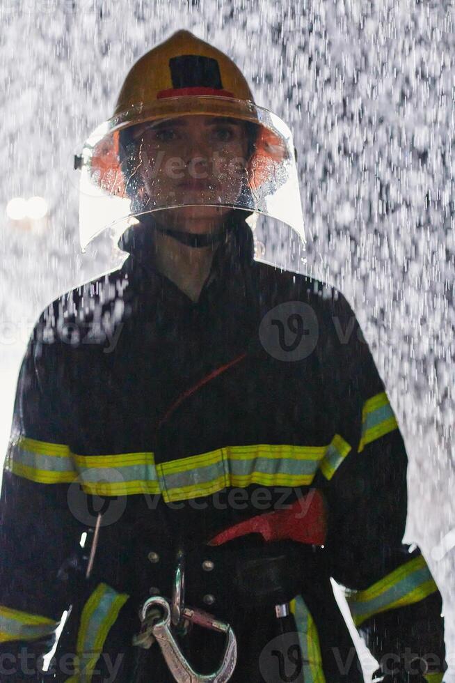 A determined female firefighter in a professional uniform striding through the dangerous, rainy night on a daring rescue mission, showcasing her unwavering bravery and commitment to saving lives. photo
