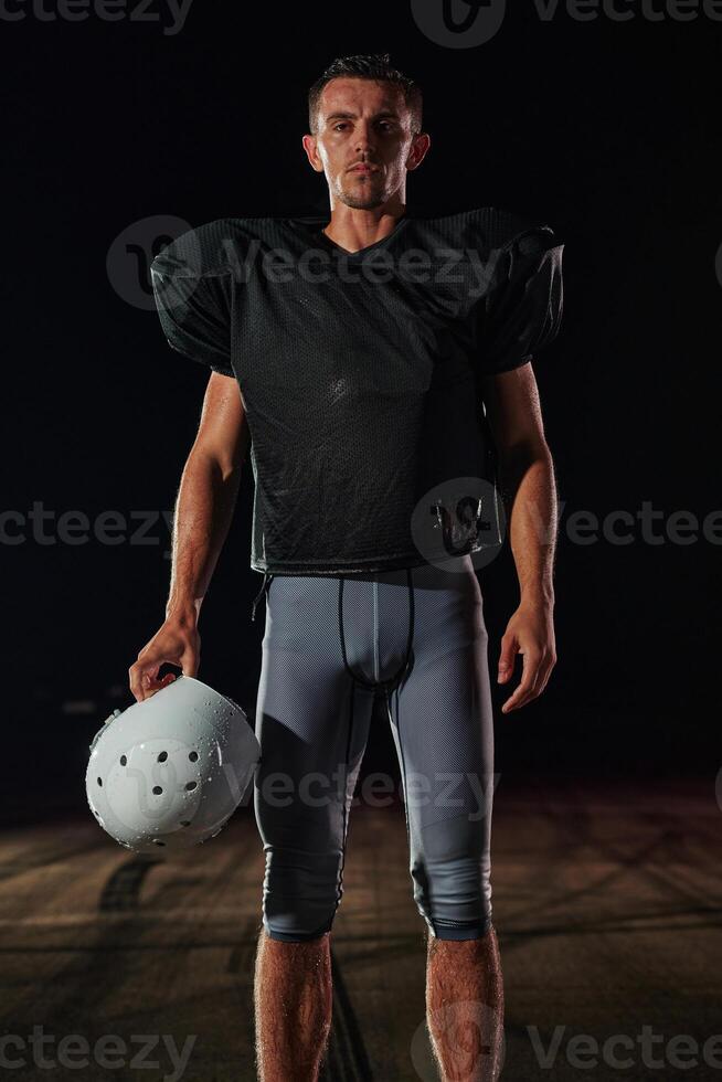 American Football Field. Lonely Athlete Warrior Standing on a Field Holds his Helmet and Ready to Play. Player Preparing to Run, Attack and Score Touchdown. photo