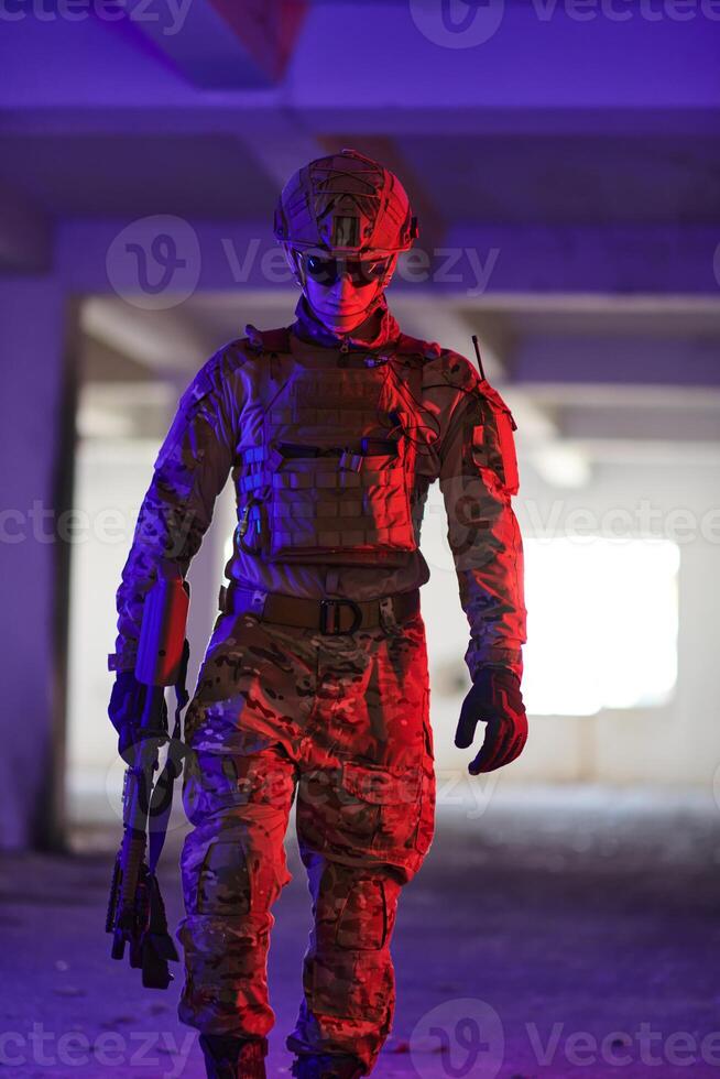 A professional soldier undertakes a perilous mission in an abandoned building illuminated by neon blue and purple lights photo