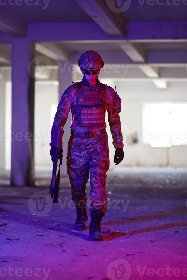 A professional soldier undertakes a perilous mission in an abandoned building illuminated by neon blue and purple lights photo