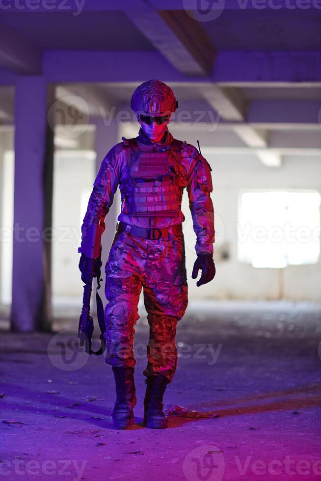 A professional soldier undertakes a perilous mission in an abandoned building illuminated by neon blue and purple lights photo