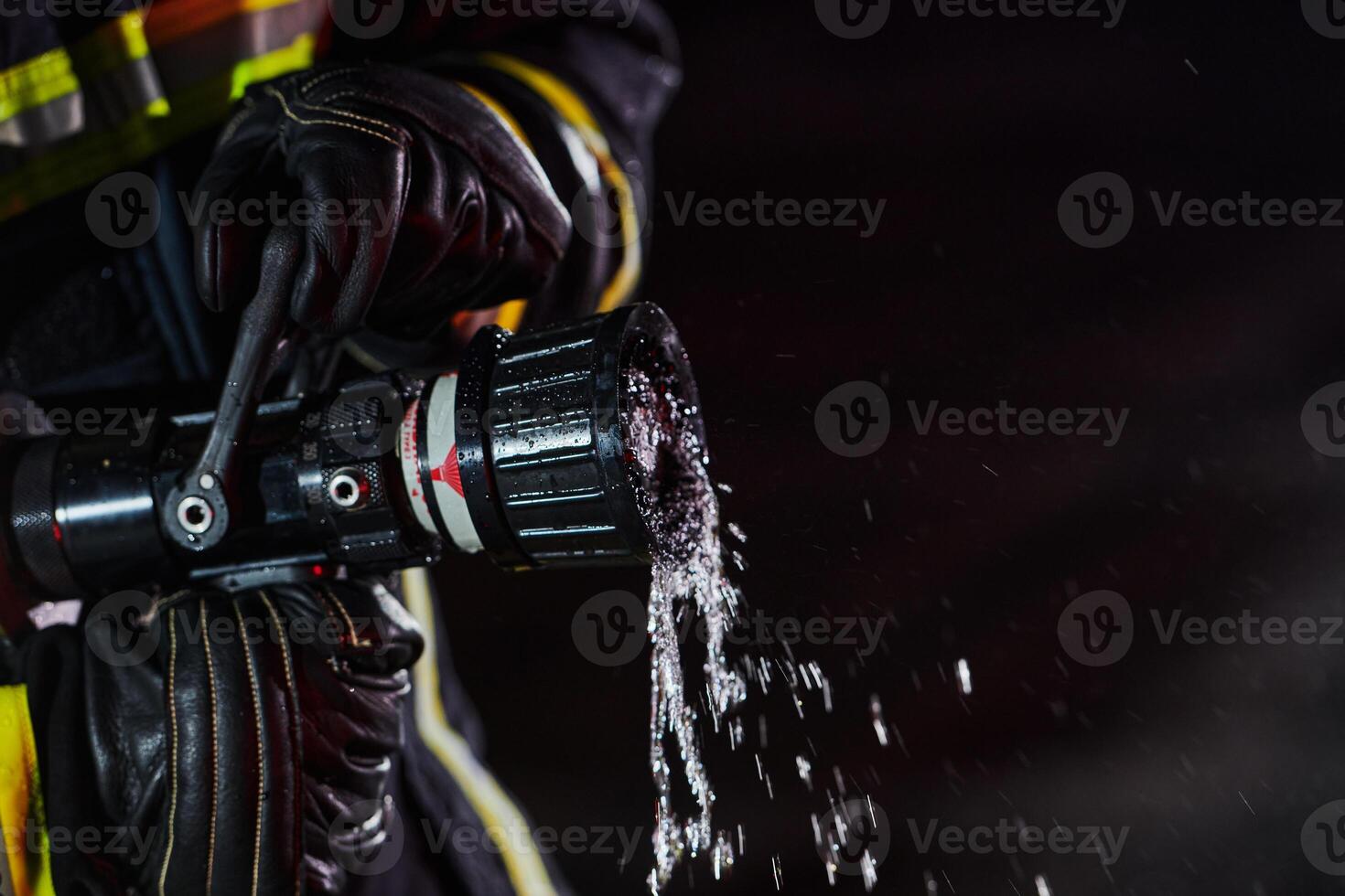 Firefighter using a water hose to eliminate a fire hazard. Team of firemen in the dangerous rescue mission. photo