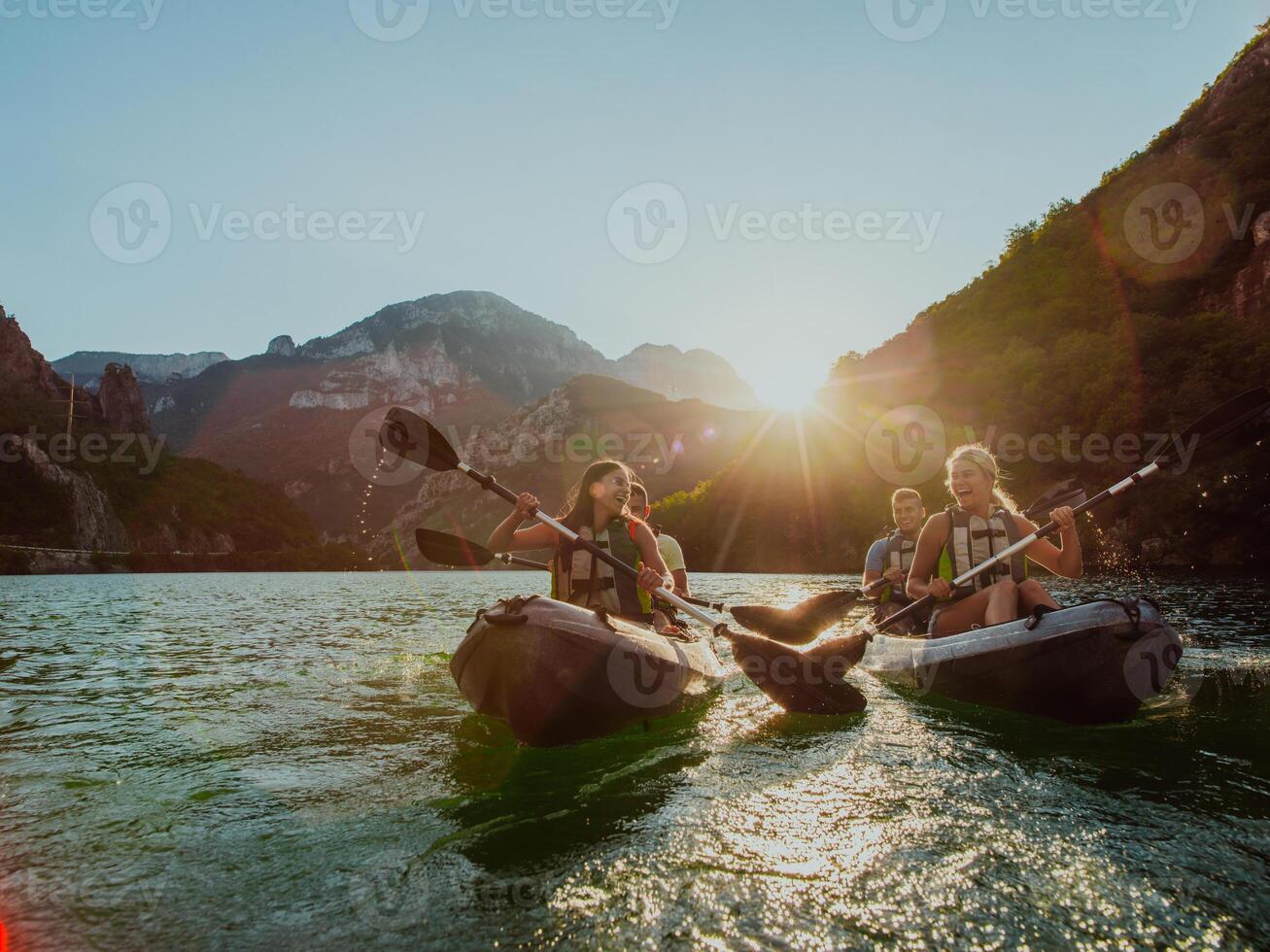 A group of friends enjoying fun and kayaking exploring the calm river, surrounding forest and large natural river canyons during an idyllic sunset. photo