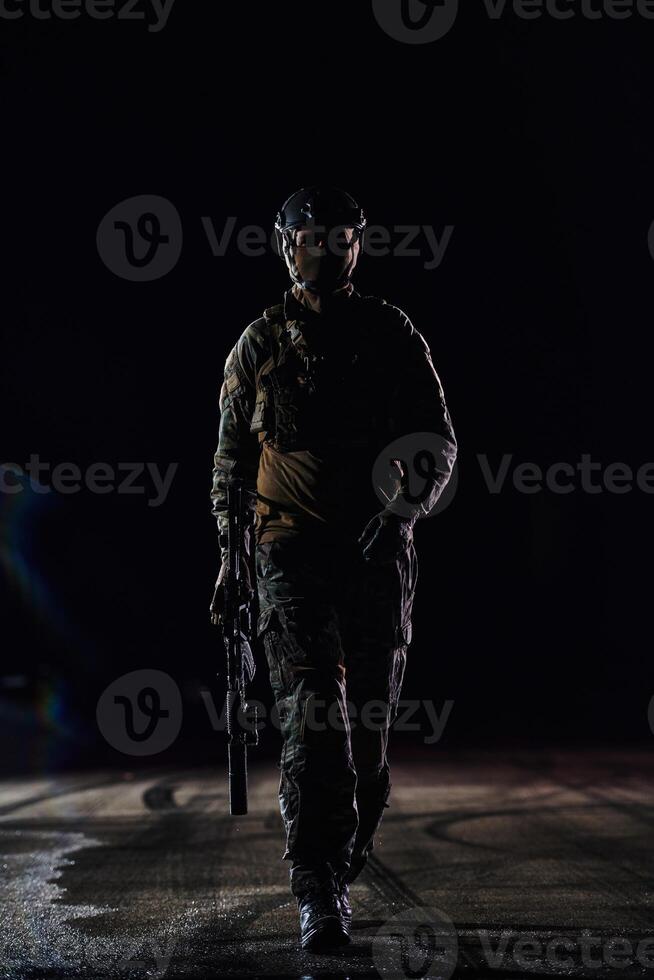A professional soldier in full military gear striding through the dark night as he embarks on a perilous military mission photo
