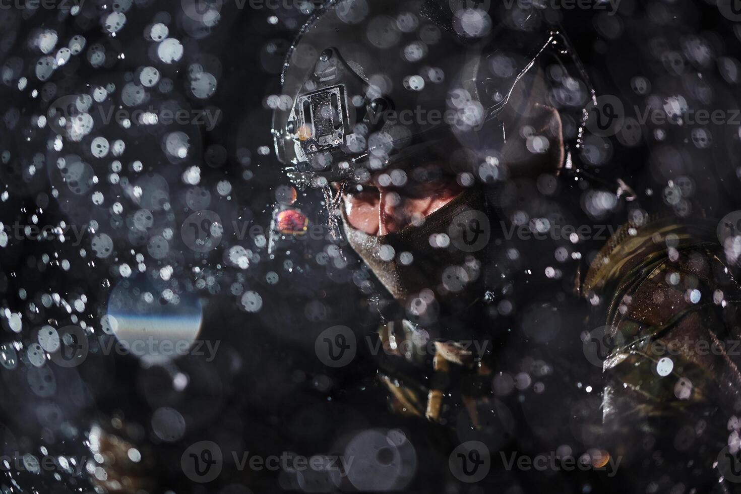 Army soldier in Combat Uniforms with an assault rifle, plate carrier and combat helmet going on a dangerous mission on a rainy night. photo